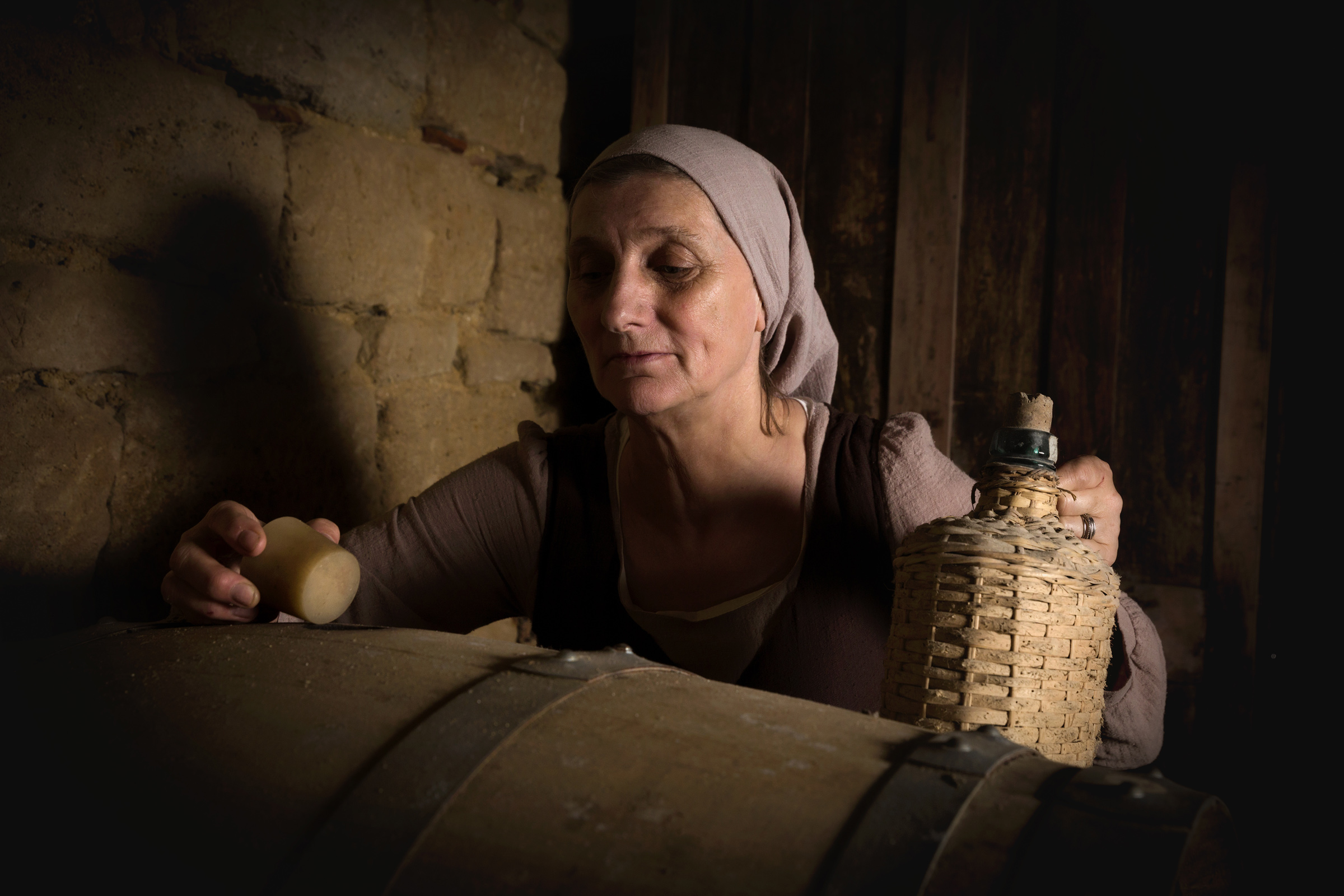 Eine Frau kontrolliert die Weinfässer im Keller.